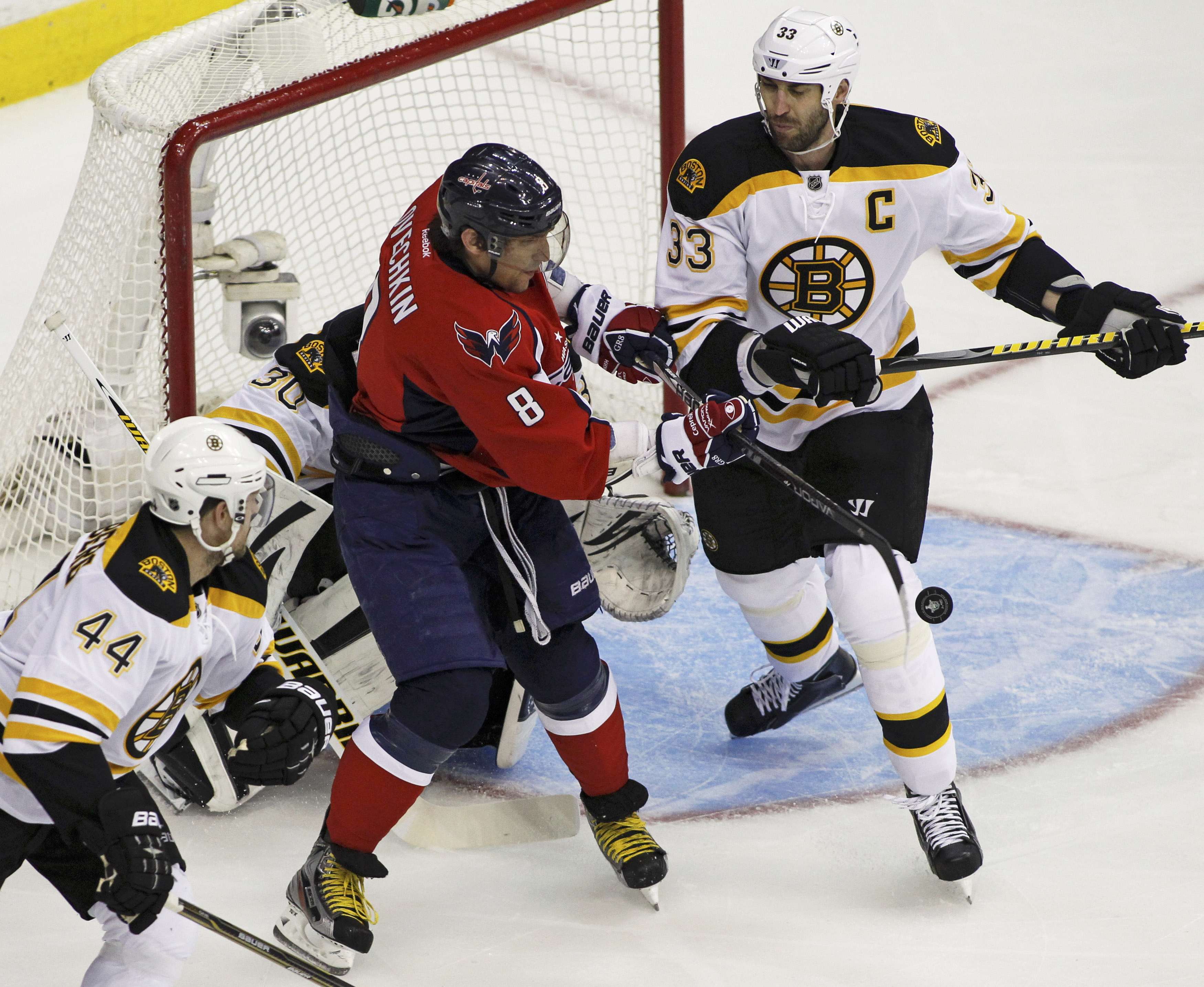Boston Bruins' Zdeno Chara (R) and Dennis Seidenberg (L) watch as Washington Capitals' Alex Ovechkin bats a puck out of the air in front of the Bruins net